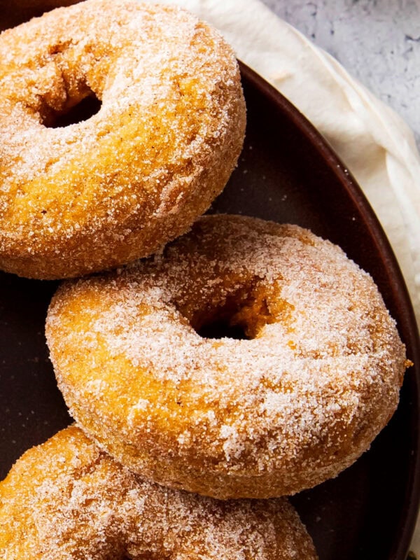 baked pumpkin donuts arranged on a plate are soft and moist with plenty of pumpkin spice flavor