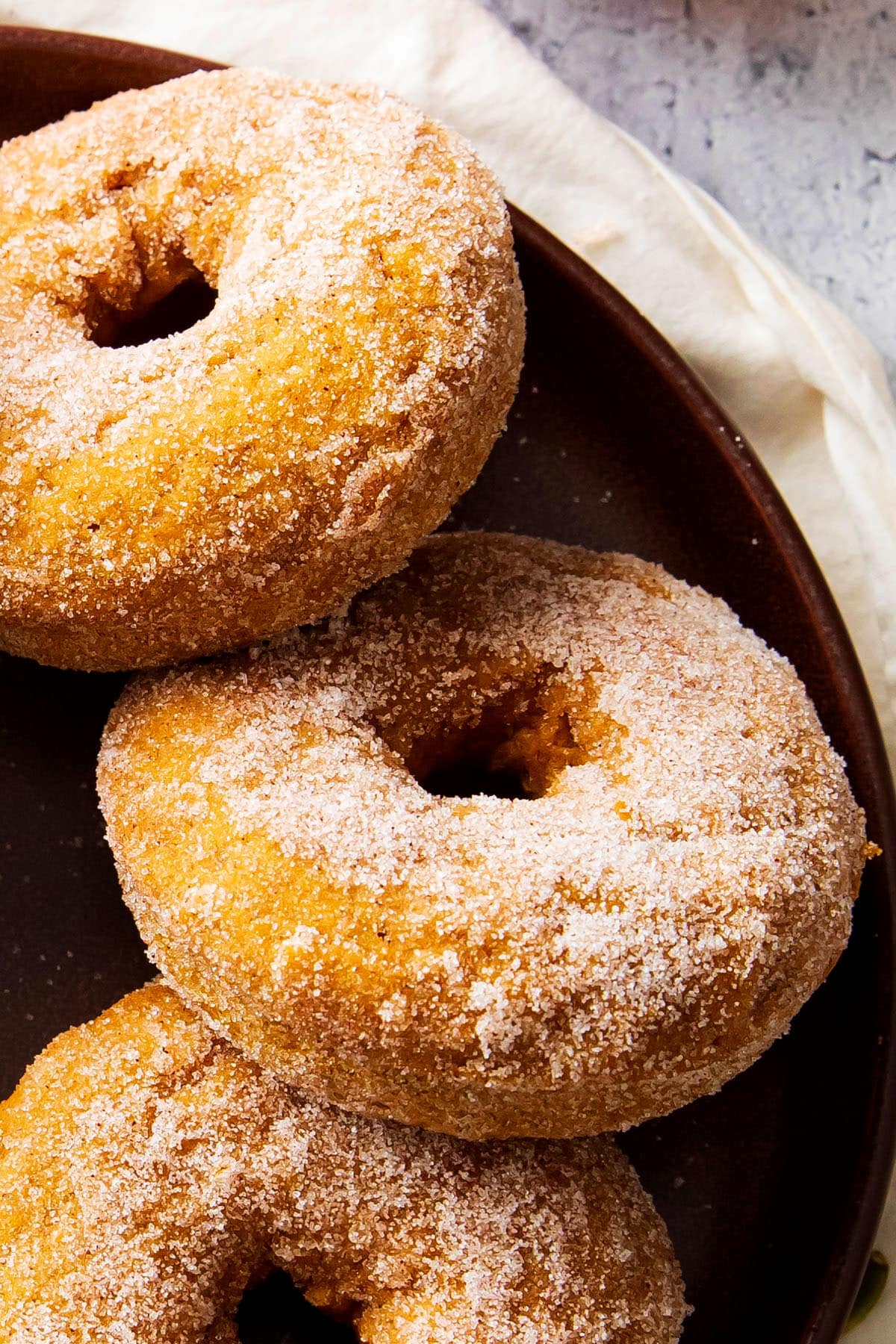 baked pumpkin donuts arranged on a plate are soft and moist with plenty of pumpkin spice flavor