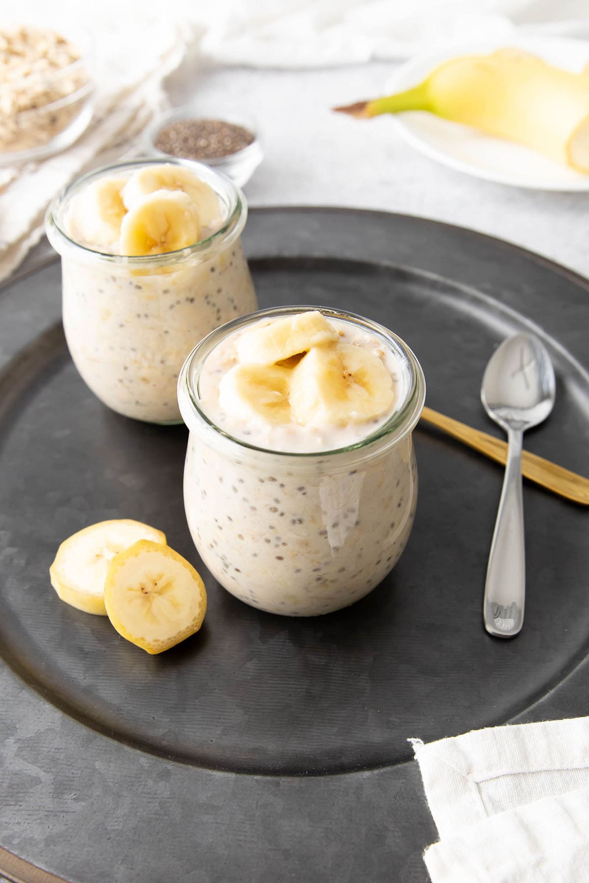 Banana overnight oats in two glass jars topped with sliced bananas