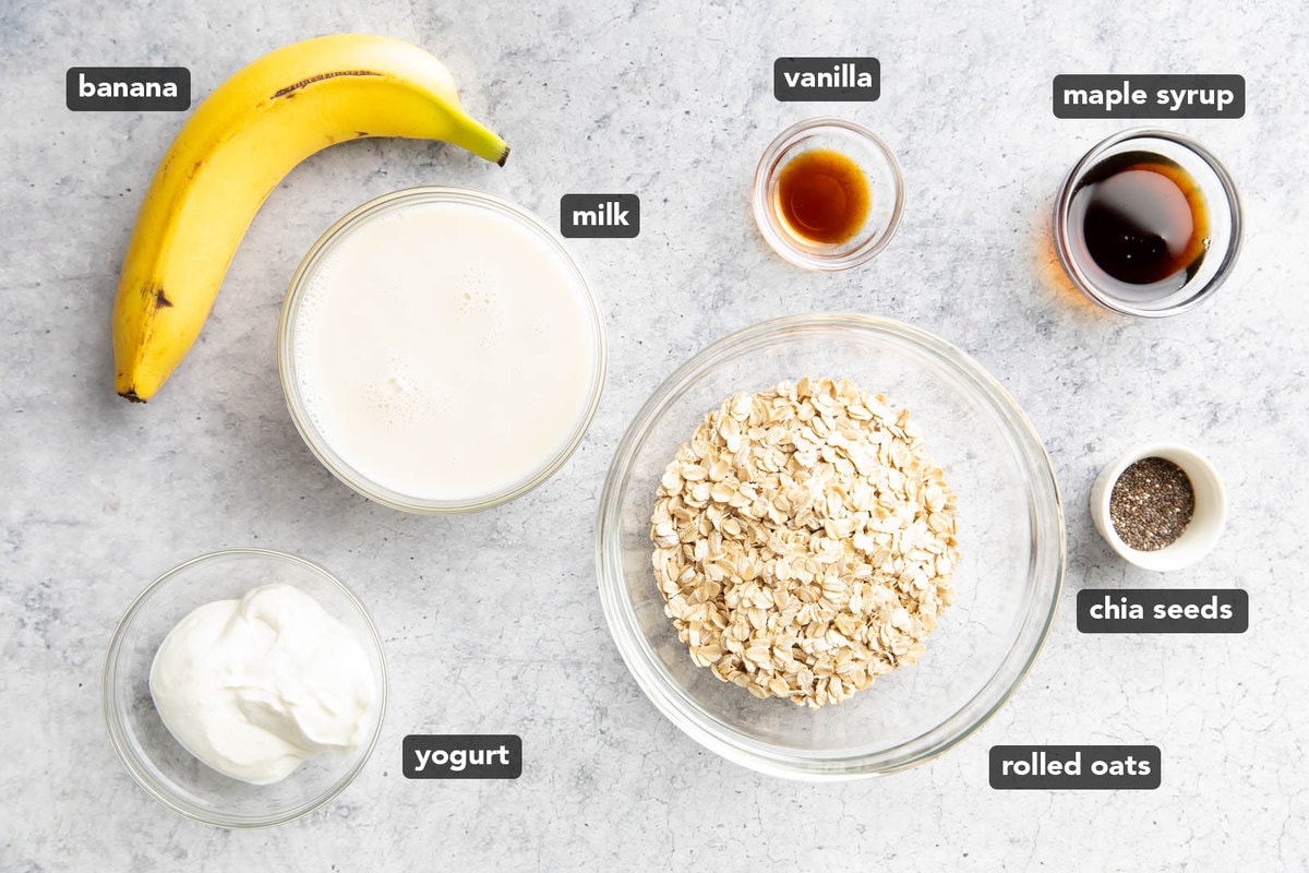 The ingredients for this banana overnight oats recipe measured into bowls including oats, milk, banana, vanilla extract, and maple syrup.