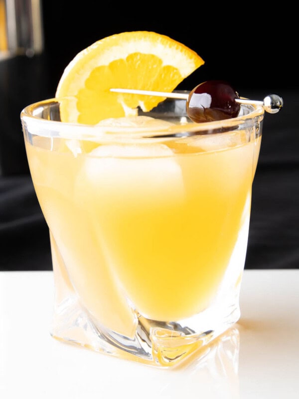 Whiskey Sour in an old fashioned glass with an orange slice and cherry garnish