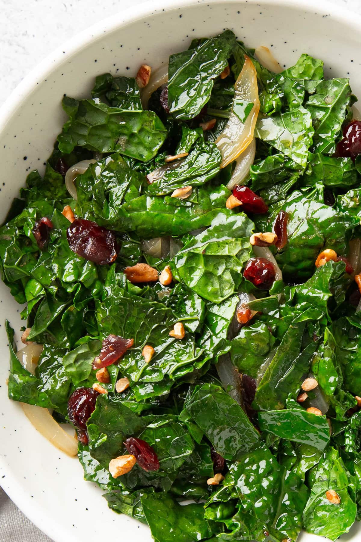 close up of sautéed kale to showcase tender texture with juicy cranberries and caramelized onions