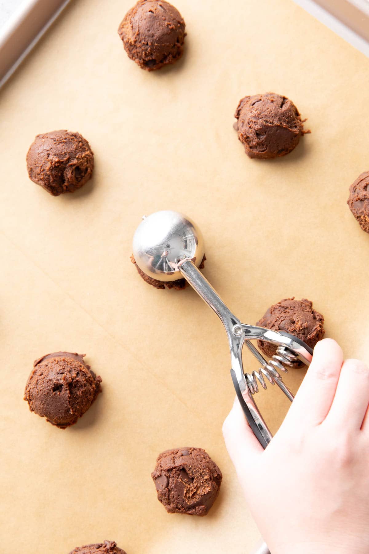 Two photos showing How to Make this chocolate baked goods – scooping dough onto lined baking sheet to bake