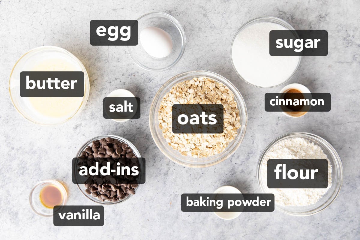 Cinnamon oatmeal cookies’ ingredients in bowls, featuring rolled oats, flour, sugar, egg, vanilla, salt, cinnamon, and baking powder.