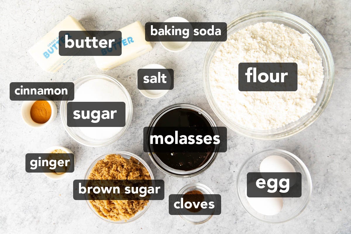 Gingersnaps Ingredients measured into mis en place bowls including unsulphured molasses, dark brown sugar, ground cloves, cinnamon, room temperature eggs and butter, and flour, baking soda, salt, and sugar.