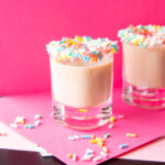 Two birthday cake shots in shot glasses with birthday sprinkles on the rims