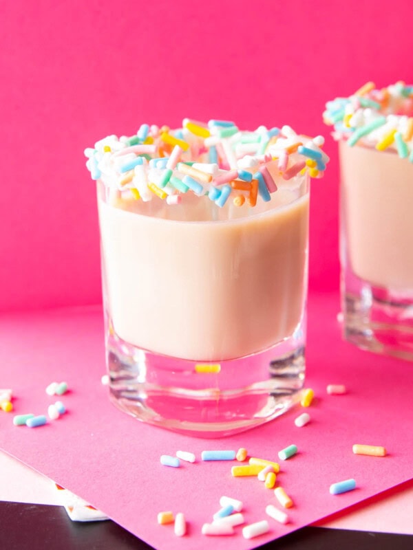 Two birthday cake shots in shot glasses with birthday sprinkles on the rims