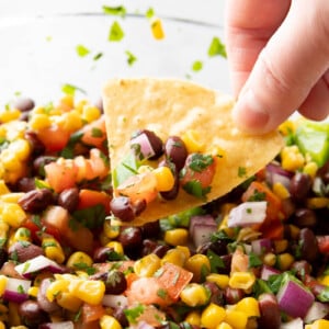 tortilla chip dipping into a bowl of black bean and corn salsa