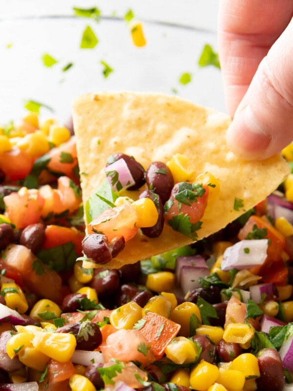 tortilla chip dipping into a bowl of black bean and corn salsa