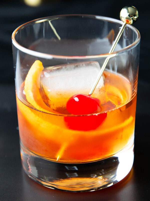 An Old Fashioned Drink recipe served in a glass with a cherry and orange slice garnish