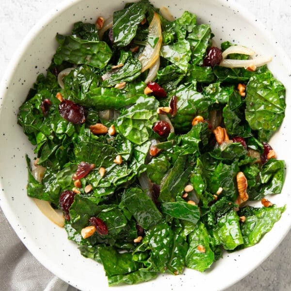 serving bowl filled with sautéed kale topped with cranberries and pecans