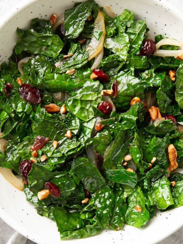 serving bowl filled with sautéed kale topped with cranberries and pecans