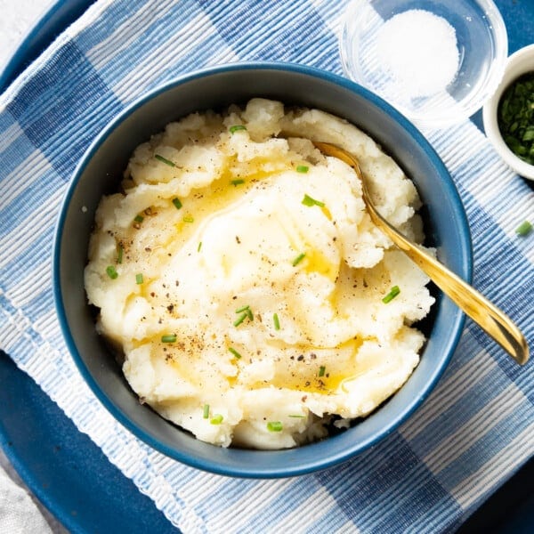 bowl of vegan mashed potatoes topped with melted vegan butter and green chives