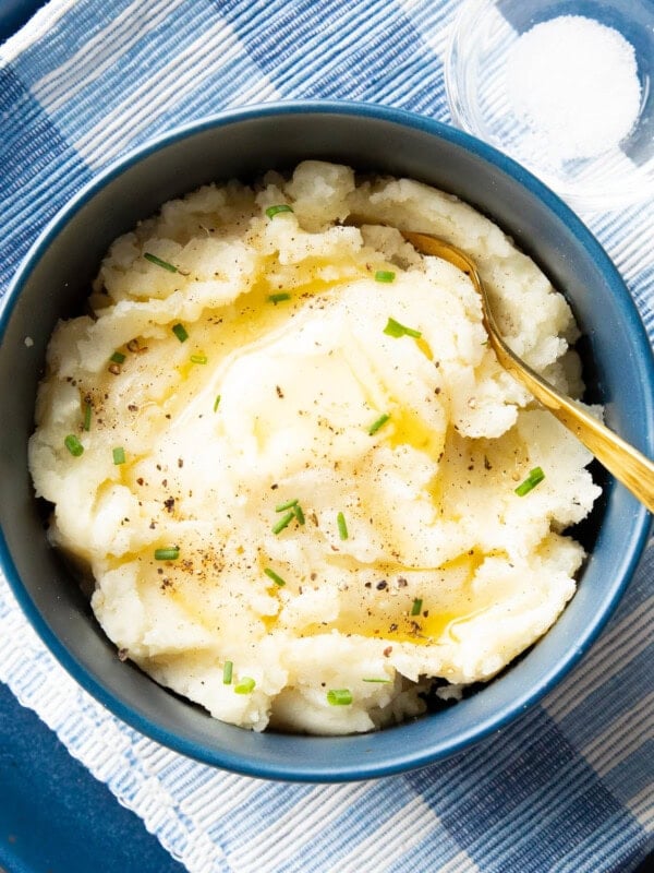 bowl of vegan mashed potatoes topped with melted vegan butter and green chives