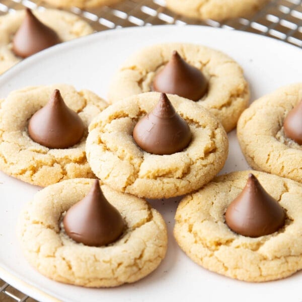 Close up of peanut butter blossoms on in a stack on a white plate