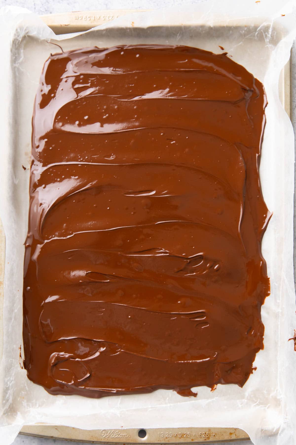 Melted chocolate spread into one even layer on the lined baking sheet