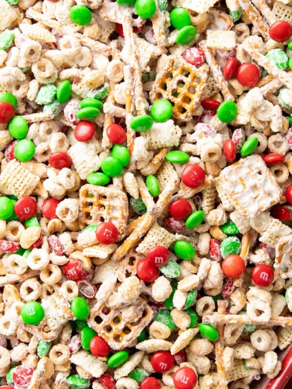 Christmas Puppy Chow is white chocolate coated Chex mix, red and green candies with festive holiday colors, and pretzels for an easy Christmas snack