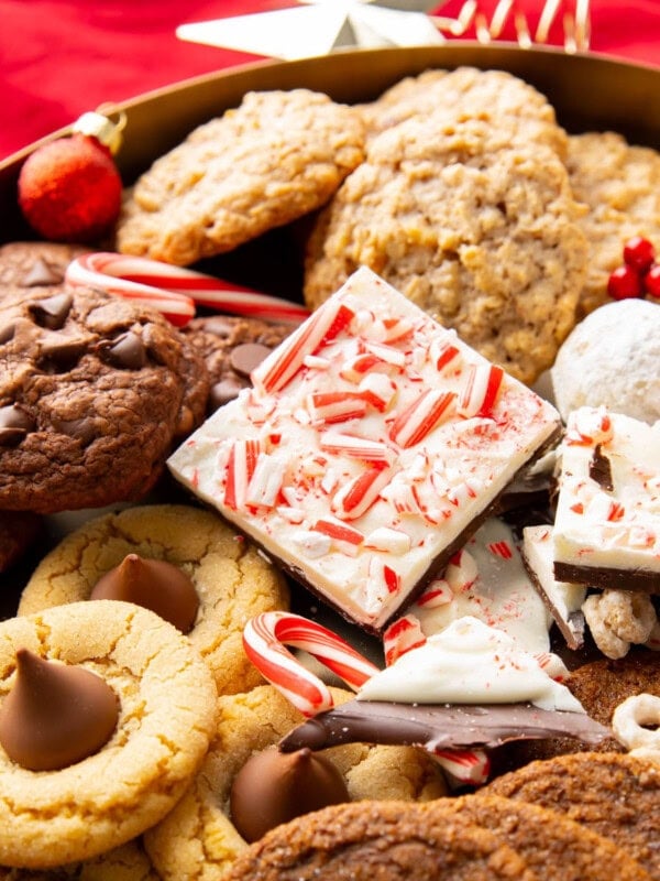 Close up of Christmas cookies and holiday cookies on a dessert platter, including: peppermint bark, snowball cookies, peanut butter blossoms, and reindeer chow