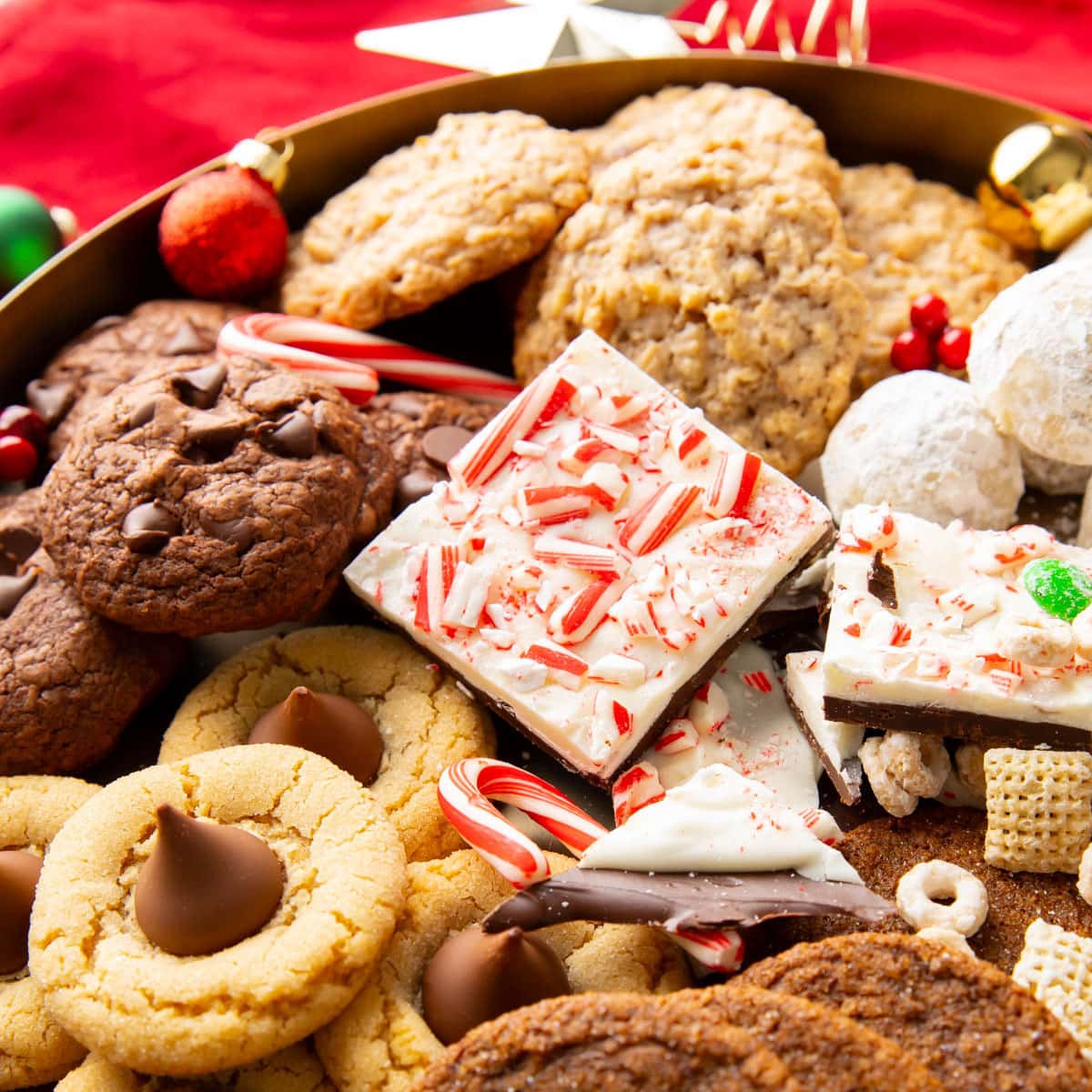 Close up of Christmas cookies and holiday cookies on a dessert platter, including: peppermint bark, snowball cookies, peanut butter blossoms, and reindeer chow