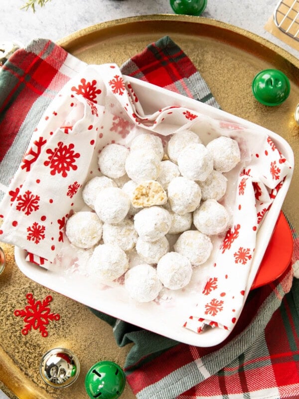 Bitten Cookie on a stack of Snowball Cookies in a serving dish