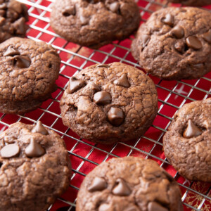 Brownie cookies cooling on a rack with melty chocolate chips on top