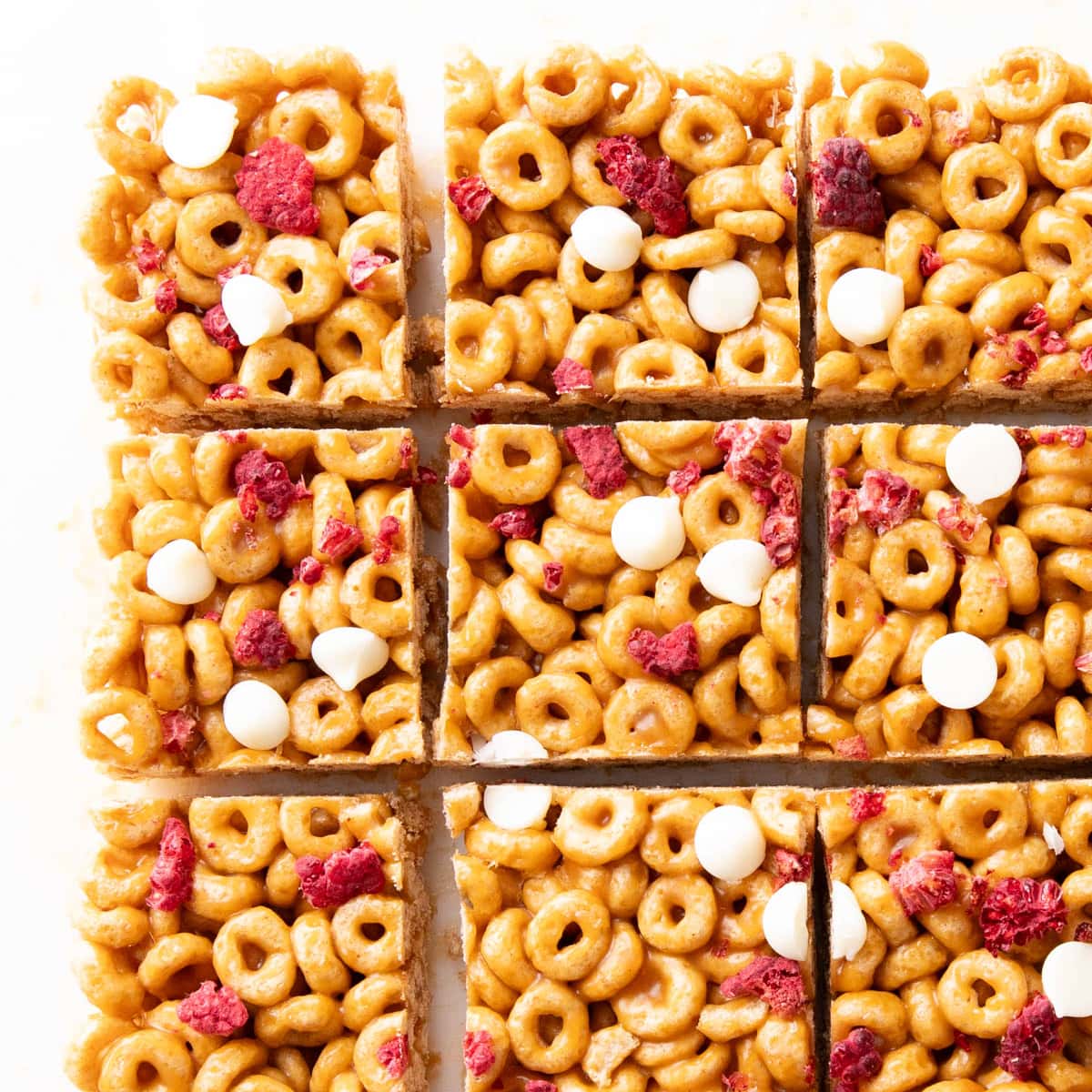 Cereal bars made with Cheerios, fruit, and chocolate chips sliced and ready to eat on a white serving tray.