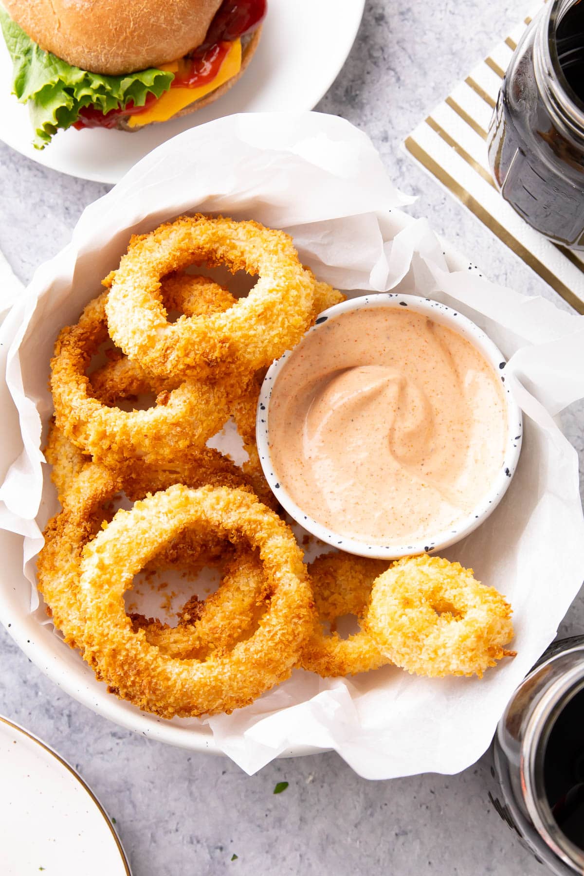 Onion ring sauce made with mayonnaise, ketchup, paprika, Cajun seasoning and more is thick and creamy in a bowl served with homemade onion rings
