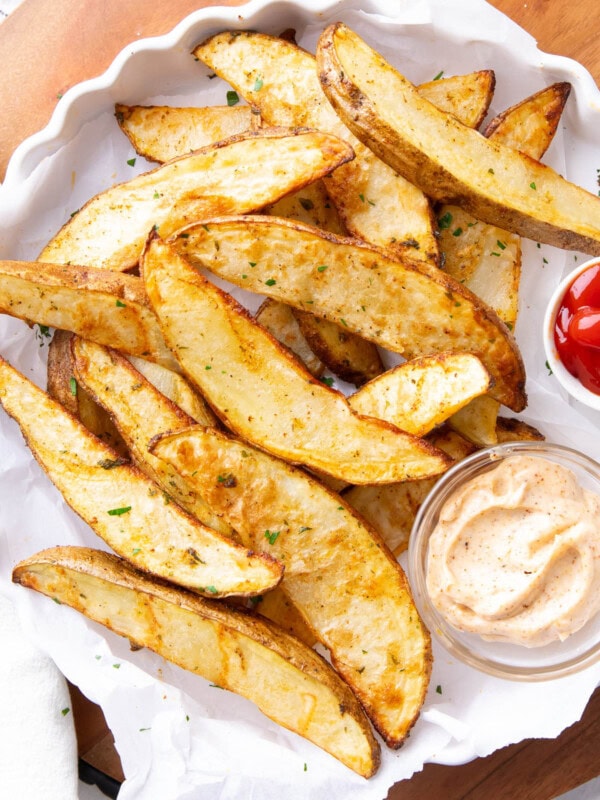 Air fryer potato wedges with crisp edges and fluffy centers sprinkled with fresh parsley and served with ketchup.