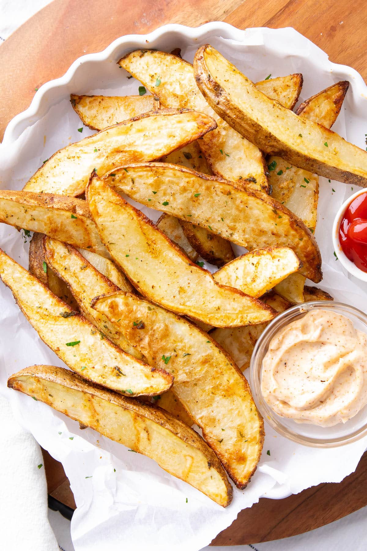 Air fryer potato wedges with crisp edges and fluffy centers sprinkled with fresh parsley and served with ketchup