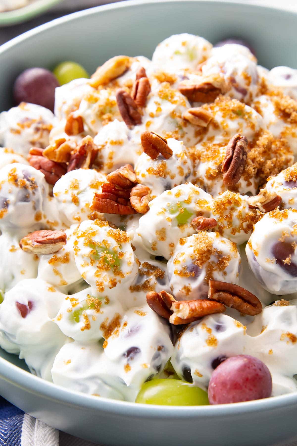 Close up of this grape salad recipe topped with pecans and brown sugar to balance the sour cream and cream cheese