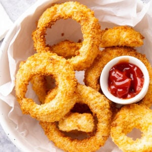 Bowl of Air Fryer Onion Rings served with ketchup.