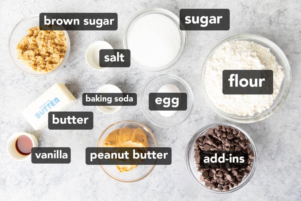 Ingredients for this peanut butter blondies recipe measured into bowls, including peanut butter, flour, egg, butter, vanilla, sugar, and baking soda.
