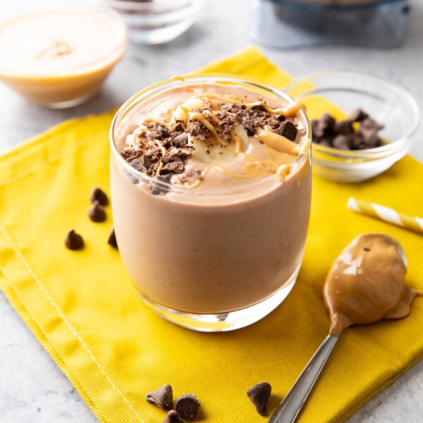 Chocolate peanut butter banana smoothie served in a glass cup topped with chocolate shavings and peanut butter drizzle