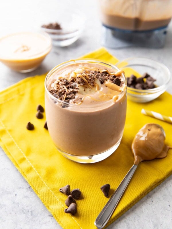 Chocolate peanut butter banana smoothie served in a glass cup topped with chocolate shavings and peanut butter drizzle