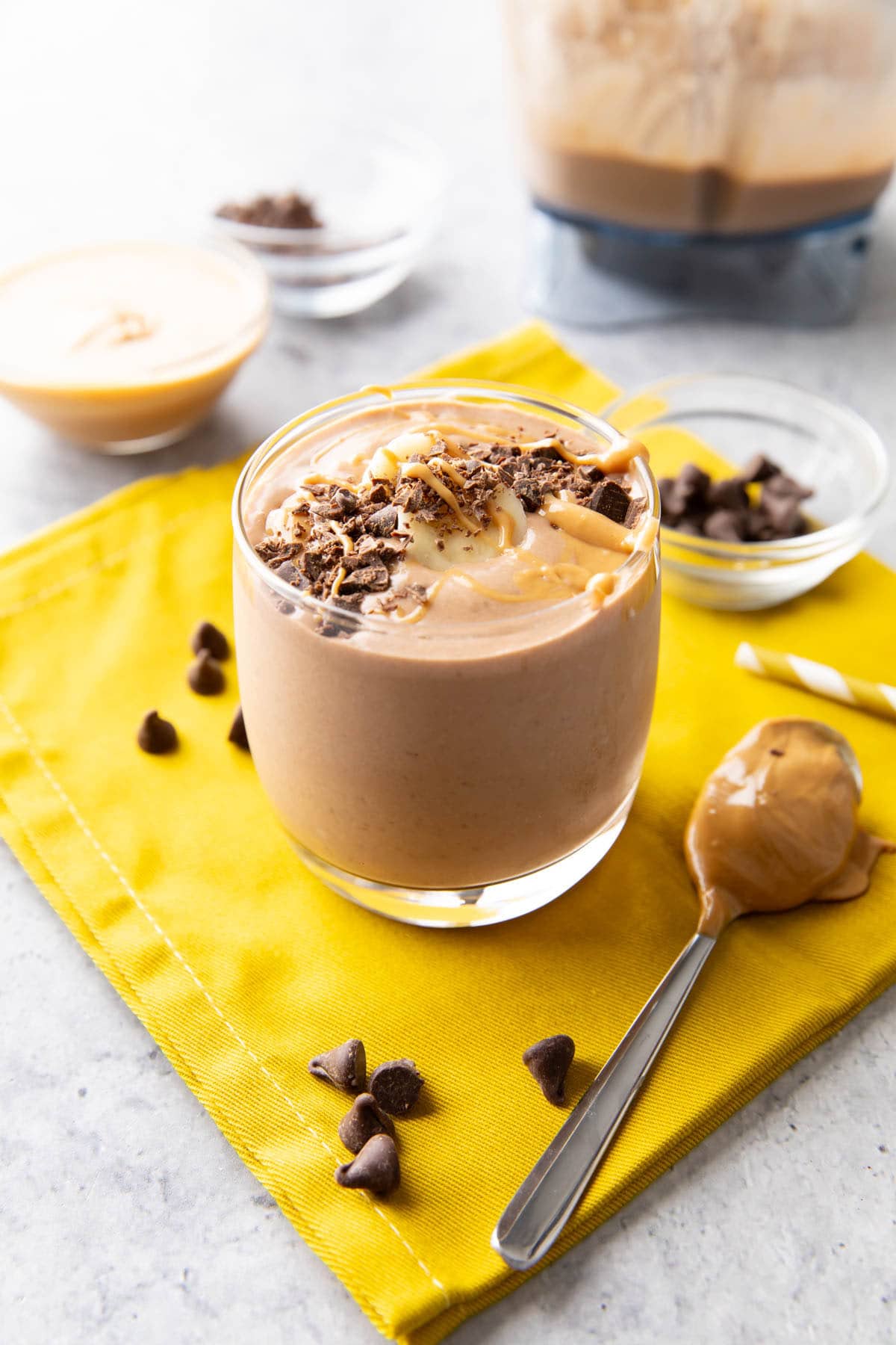 Chocolate peanut butter smoothie served in a glass cup topped with chocolate shavings and peanut butter drizzle