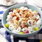 A serving bowl filled with Grape Salad coated in creamy vanilla dressing and packed with juicy red and green grapes topped with brown sugar and pecans