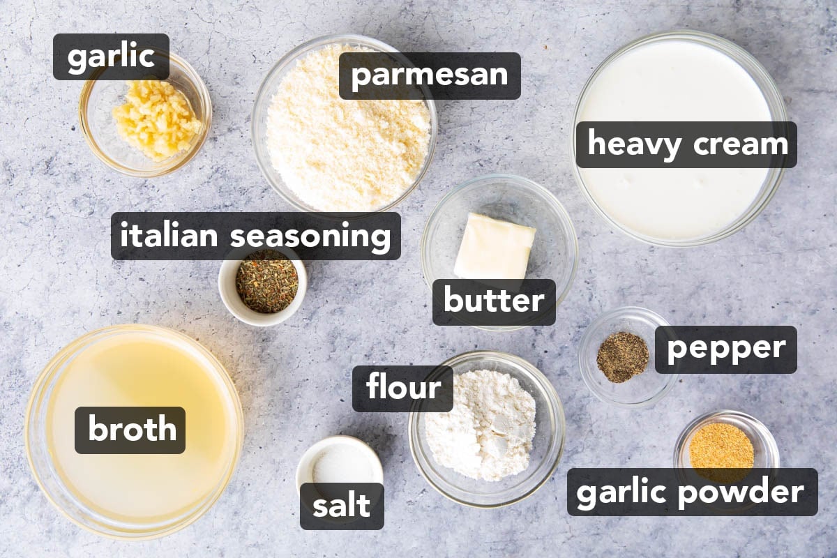 Garlic parmesan sauce ingredients in prep bowls, including parmesan, heavy cream, butter, chicken broth, Italian seasoning, black pepper, salt, minced garlic, and garlic powder