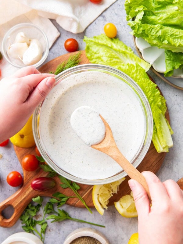 Holding a spoon full of thick and creamy ranch dressing packed full of delicious herbs and seasonings