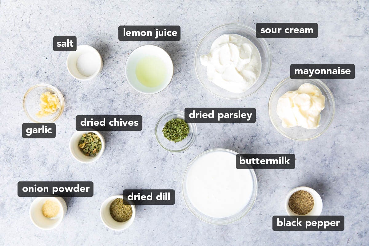 The ingredients for this ranch dressing recipe measured into prep bowls including mayonnaise, sour cream, lemon juice, garlic, parsley and other spices.