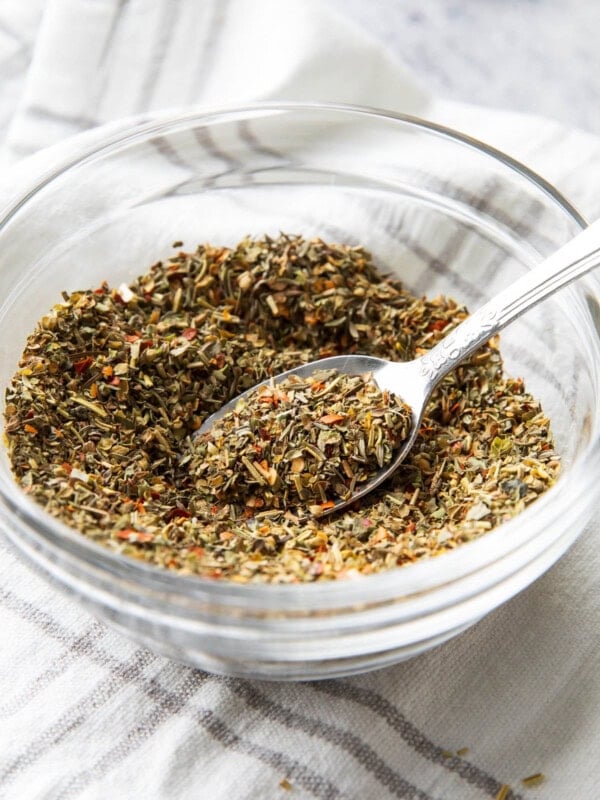 A bowl of Italian seasoning with a spoon in it