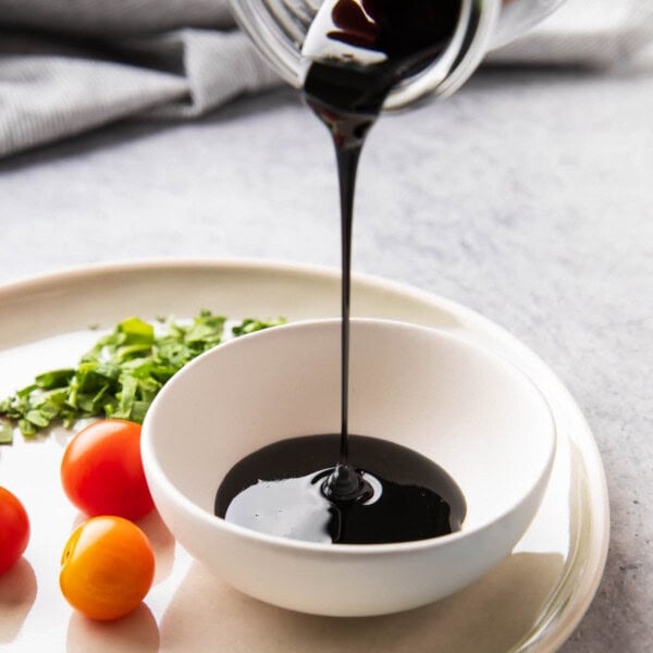 Pouring a jar of balsamic glaze into a serving bowl for dipping with veggies, bruschetta, and more.