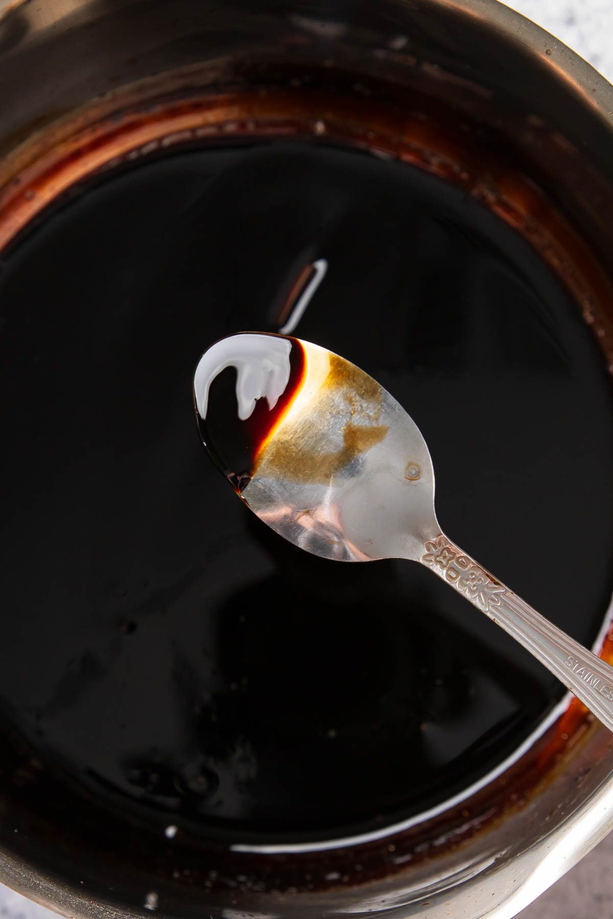 coating the back of a spoon in balsamic glaze recipe to show that its thick enough to stop cooking and the recipe is complete