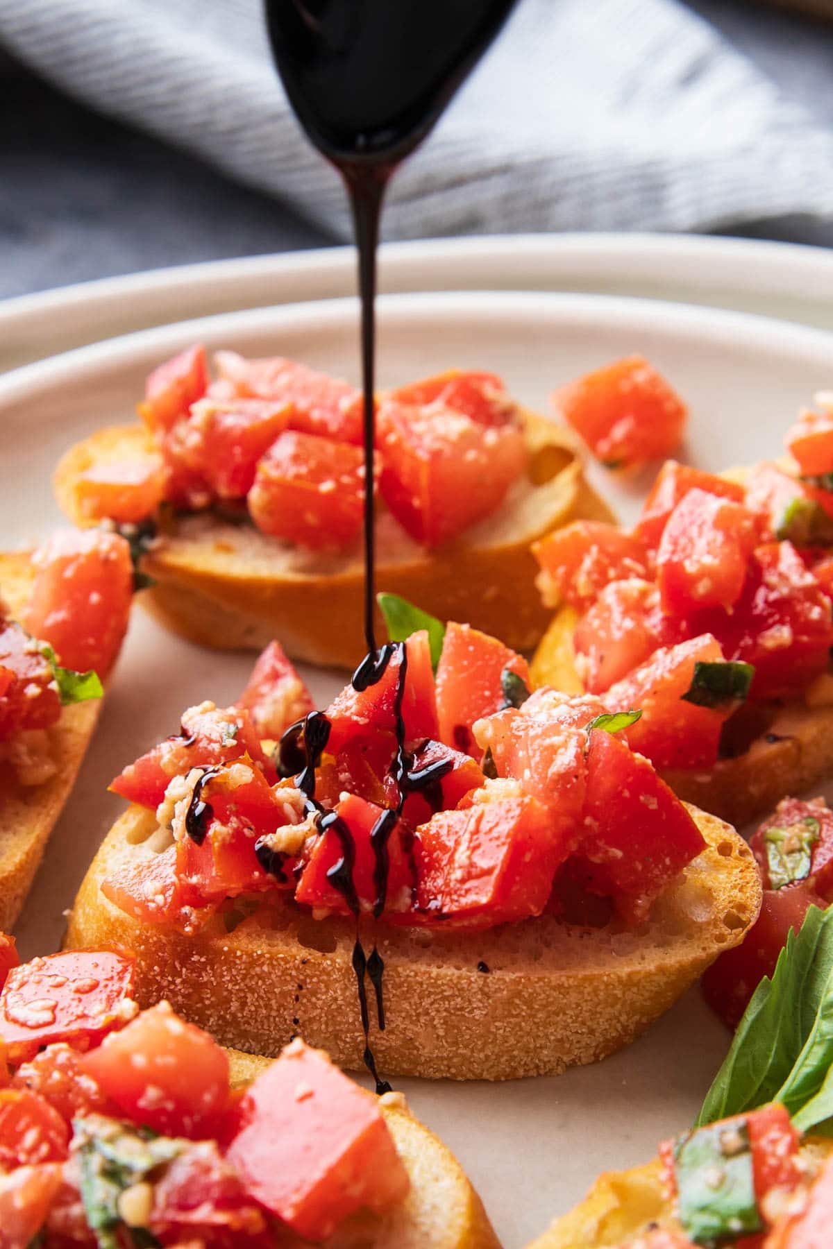 Drizzling balsamic glaze over this classic Italian antipasto, bruschetta, packed with tomatoes and basil atop toasted olive oil baguettes.