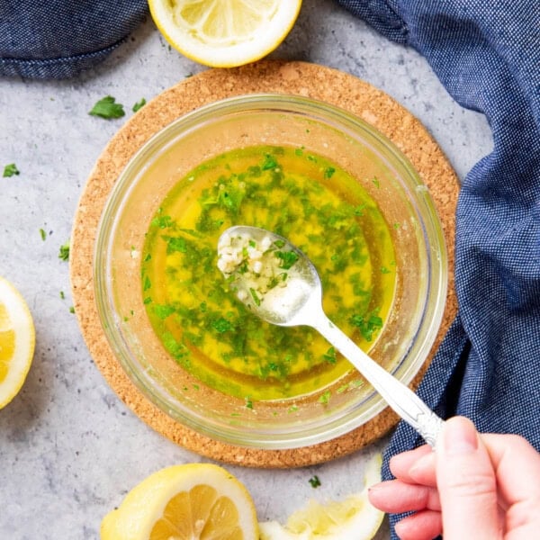 Spooning garlic butter sauce over a bowl with melted, fragrant garlic, parsley, and seasonings