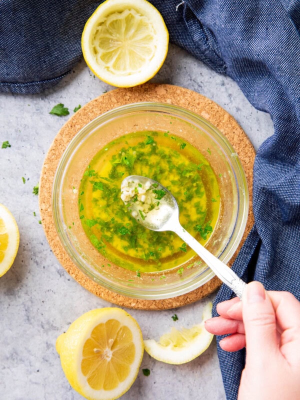 Spooning garlic butter sauce over a bowl with melted, fragrant garlic, parsley, and seasonings