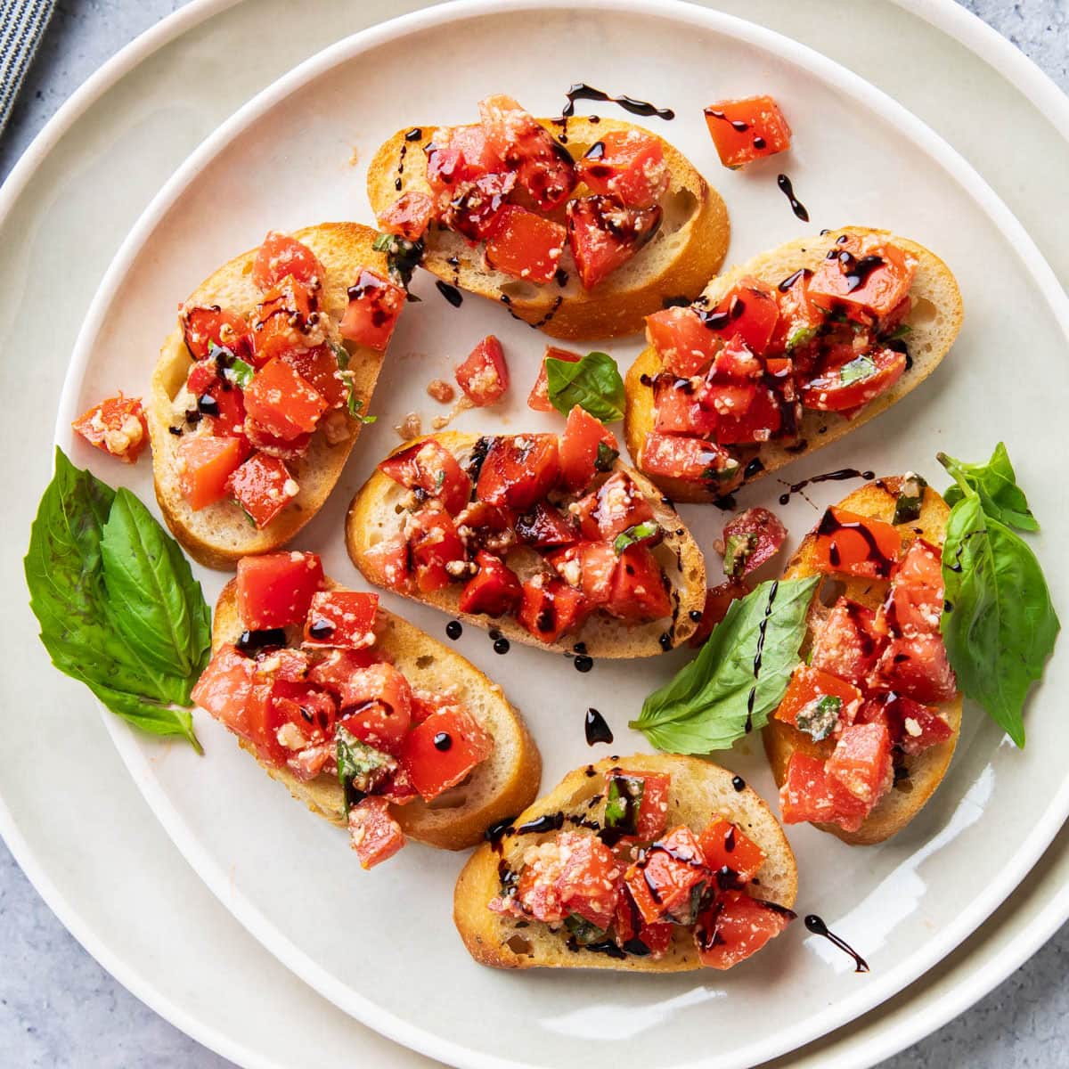 Platter of this Italian antipasto on toasted, sliced baguettes topped with tomato, basil, parmesan, and Italian seasoned topping with olive oil.