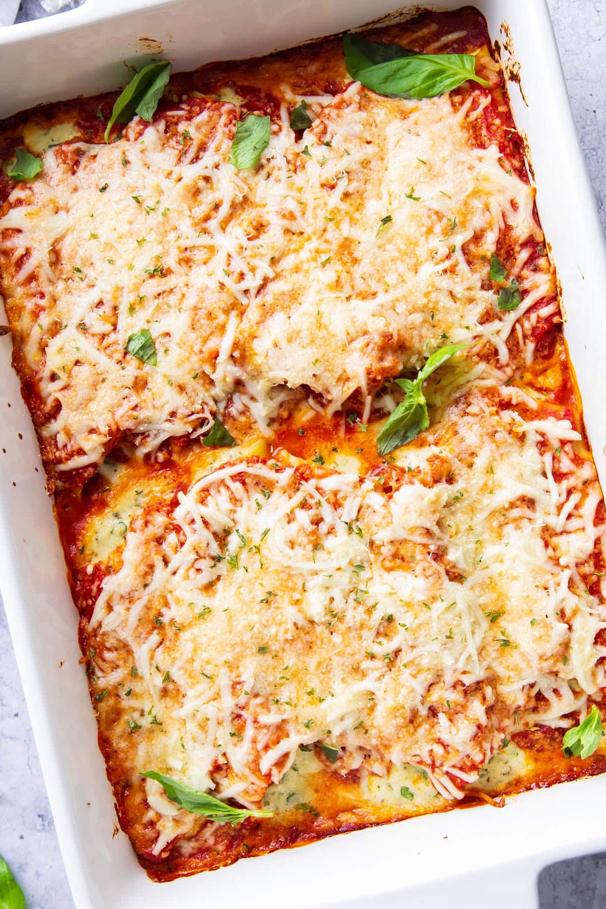 Fresh baked manicotti recipe in a ceramic dish with melted, baked cheese, spinach, and marinara