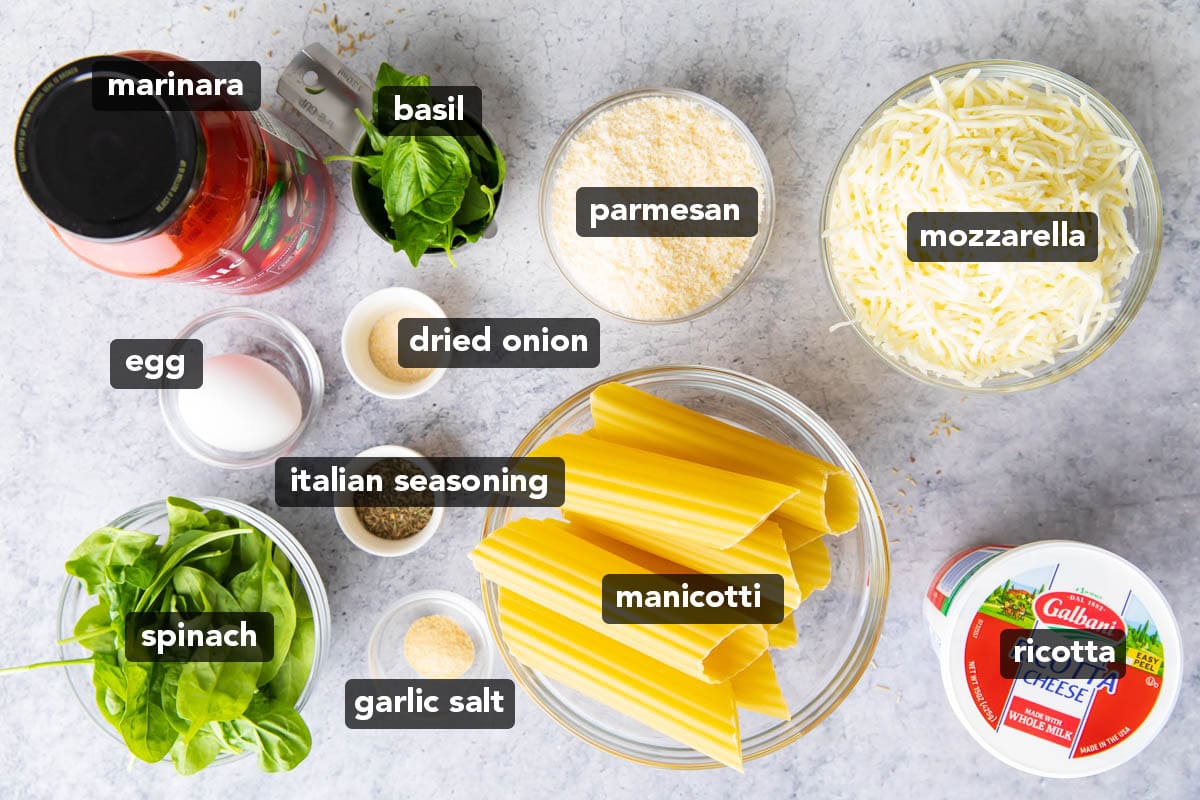 Stuffed Manicotti Recipe ingredients including marinara, manicotti pasta, parmesan cheese, mozzarella cheese, ricotta cheese, salt and pepper, egg, spinach and basil