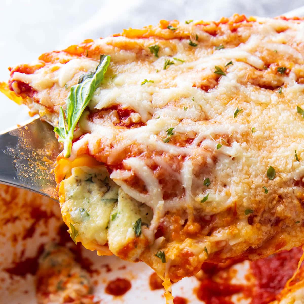 featured image with easy baked manicotti scooped up in a spatula topped with cheese