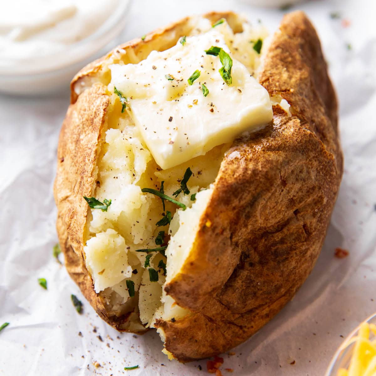 featured image with air fryer baked potato topped with a pat of butter and chives